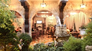 An indoor courtyard with stone arches, a fountain, and tables and chairs for dining. - Hunter Prince Castle Hotel  (Turda)