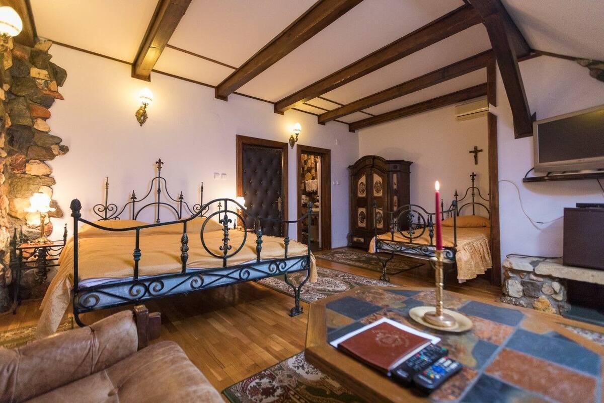 A cozy room with a bed, a wooden cabinet, a television, and a stone wall.