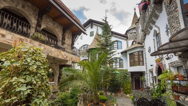A courtyard with stone buildings, potted plants, and outdoor seating. - Hunter Prince Castle Hotel  (Turda)
