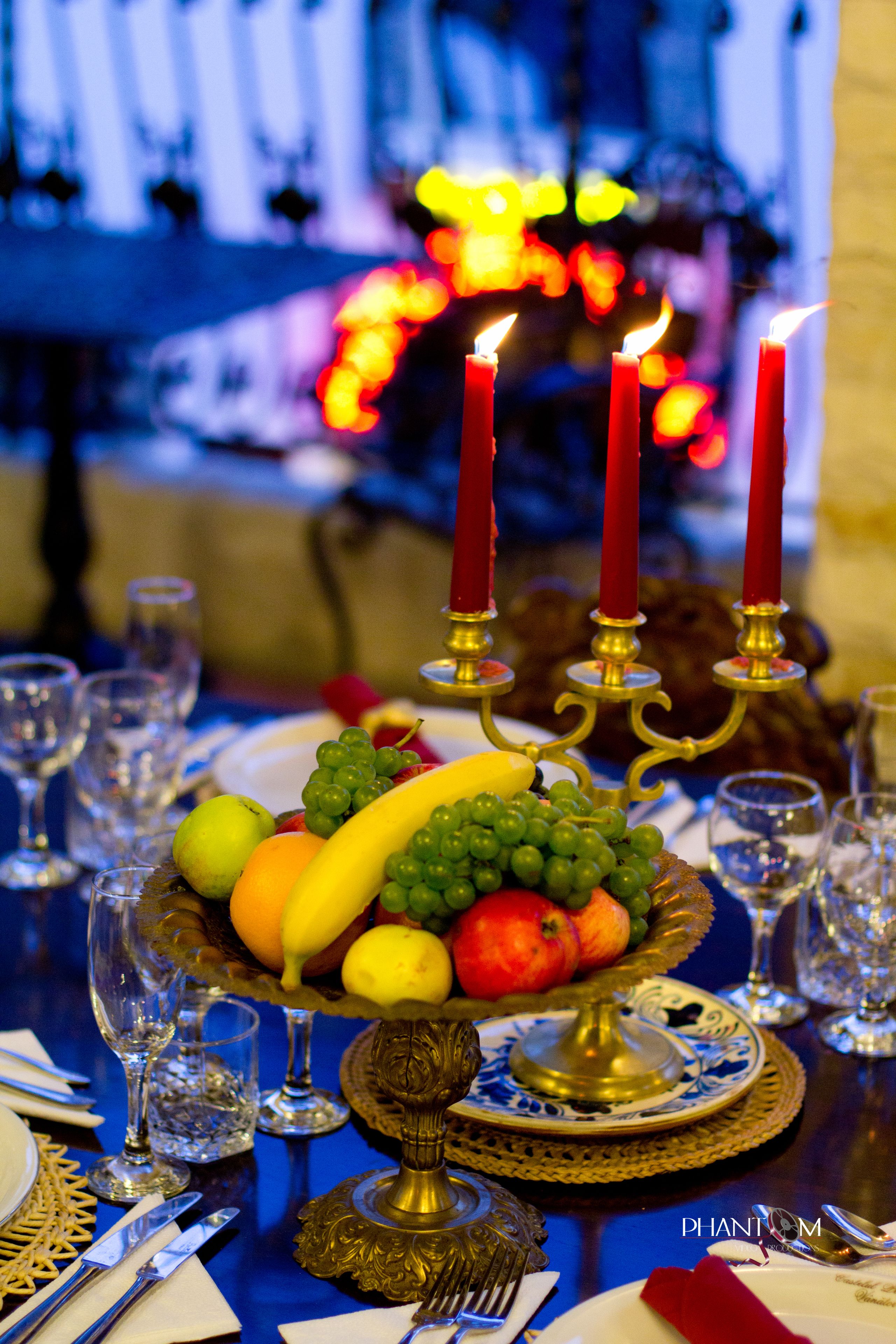 A table set with fine china, silverware, and a fruit bowl.