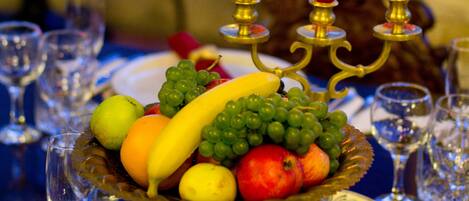 A table set with fine china, silverware, and a fruit bowl.
