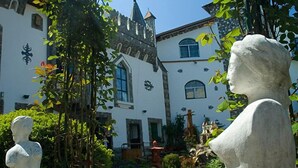 A courtyard with statues, a building with a turret, and a fountain. - Hunter Prince Castle Hotel  (Turda)