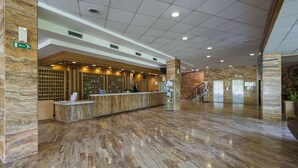 A hotel reception area with a marble floor, a reception desk, and a staircase leading to elevators. - Hotel Termal - Sava Hotels & Resorts (Moravske Toplice)
