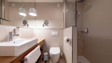 Een moderne badkamer met een wastafel, toilet en douche.