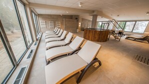 A spa area with multiple massage tables arranged in a row, large windows, and a wooden reception desk. - Hotel Termal - Sava Hotels & Resorts (Moravske Toplice)
