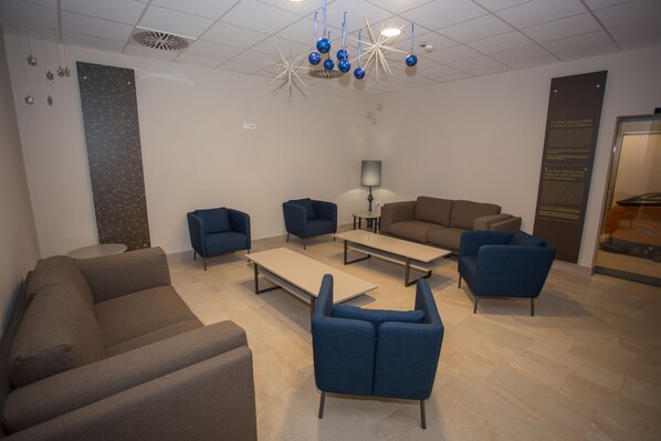 Un área de espera moderna con sofás, sillones y una mesa de centro.