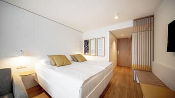 Una habitación de hotel moderna con cama, mesita de noche y televisor montado en la pared.