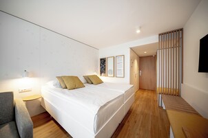 Una habitación de hotel moderna con cama, mesita de noche y televisor montado en la pared.