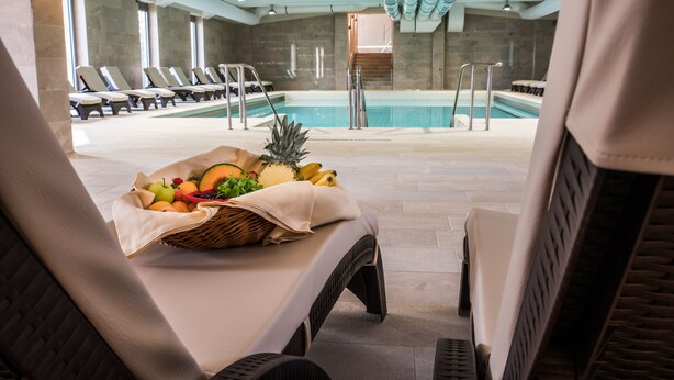 A poolside area with lounge chairs, a fruit basket, and a view of the pool. - Hotel Termal - Sava Hotels & Resorts (Moravske Toplice)