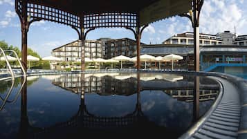 Una piscina cubierta, una piscina al aire libre, tumbonas