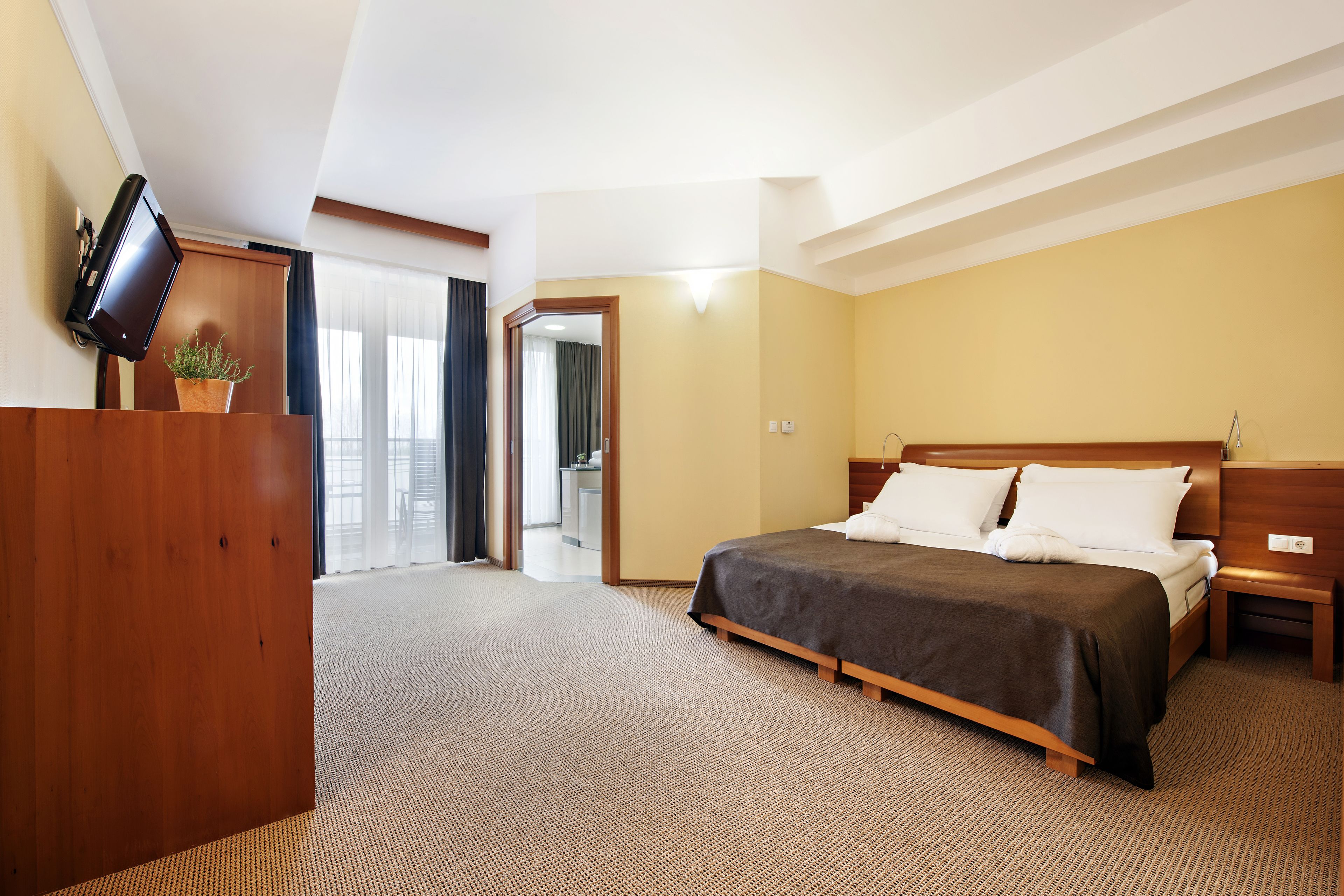 Een hotelkamer met een bed, nachtkastje en bureau met een flatscreen televisie.