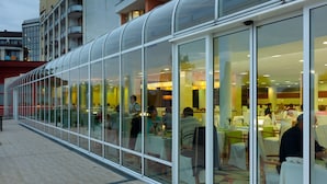 A modern restaurant with a glass facade, outdoor seating, and a view of the cityscape. - Hotel Livada Prestige - Sava Hotels & Resorts (Moravske Toplice)