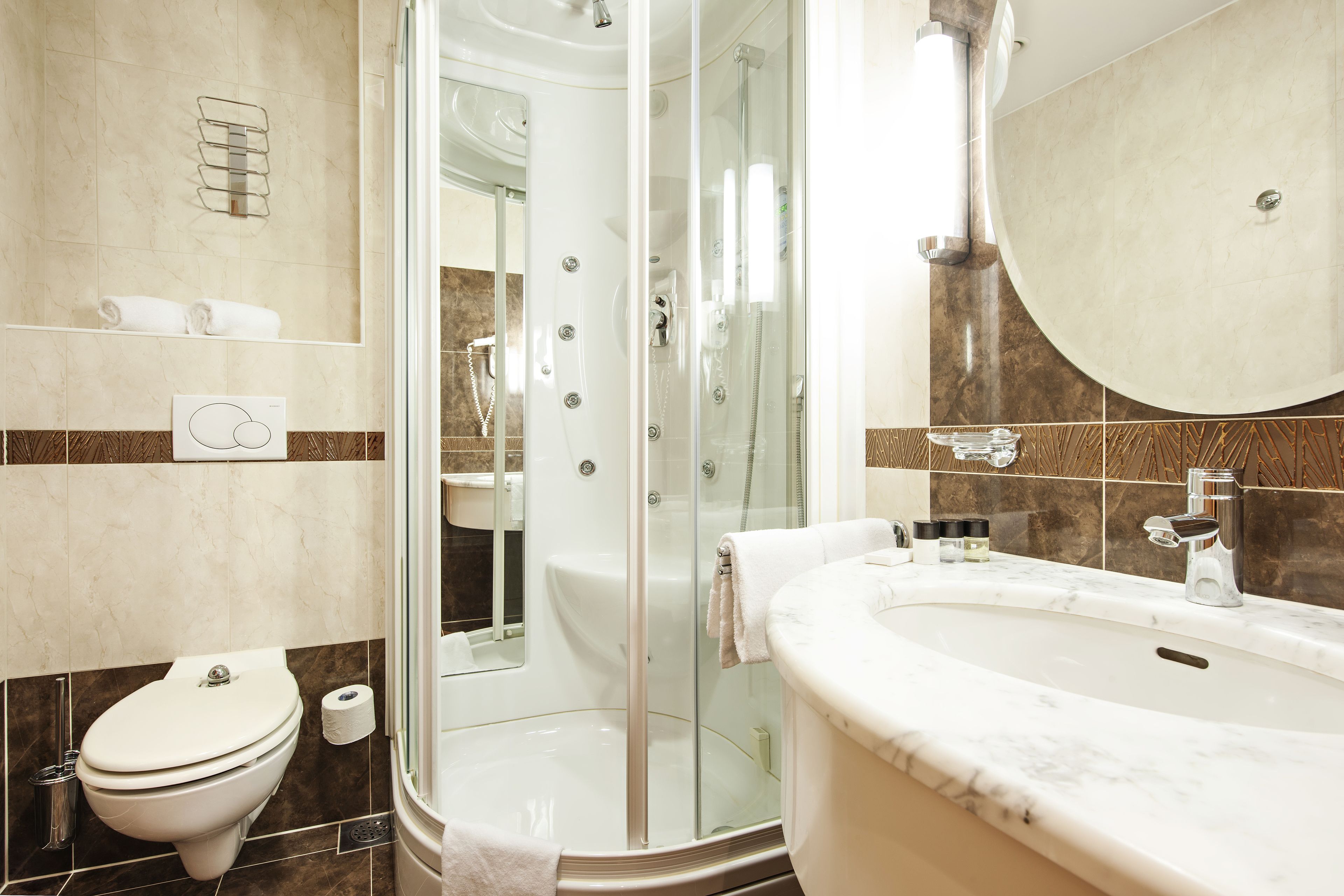Un baño moderno con cabina de ducha de vidrio, lavamanos de mármol y un inodoro.