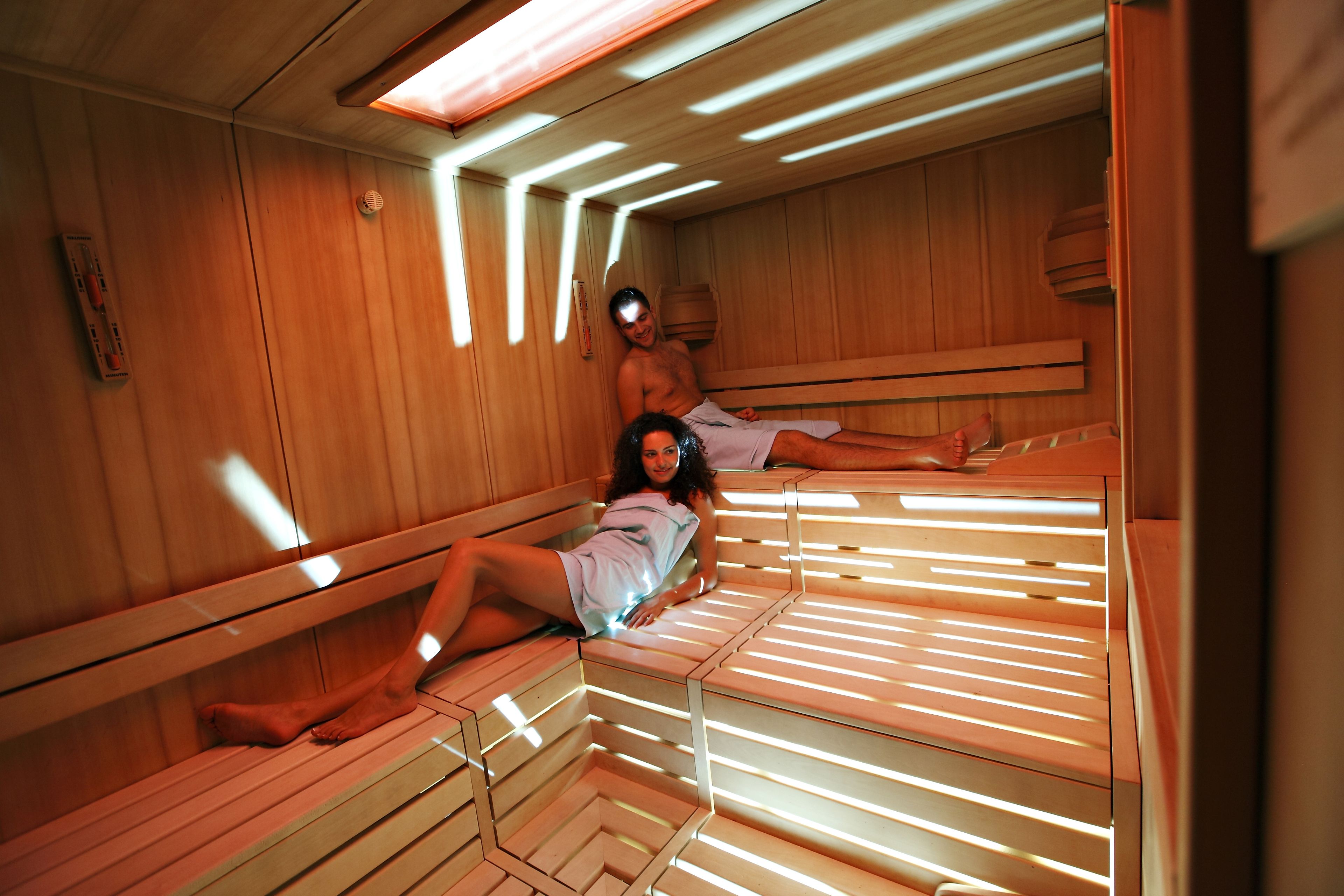 Una sauna con bancos de madera y asientos de listones, dispuestos en fila.