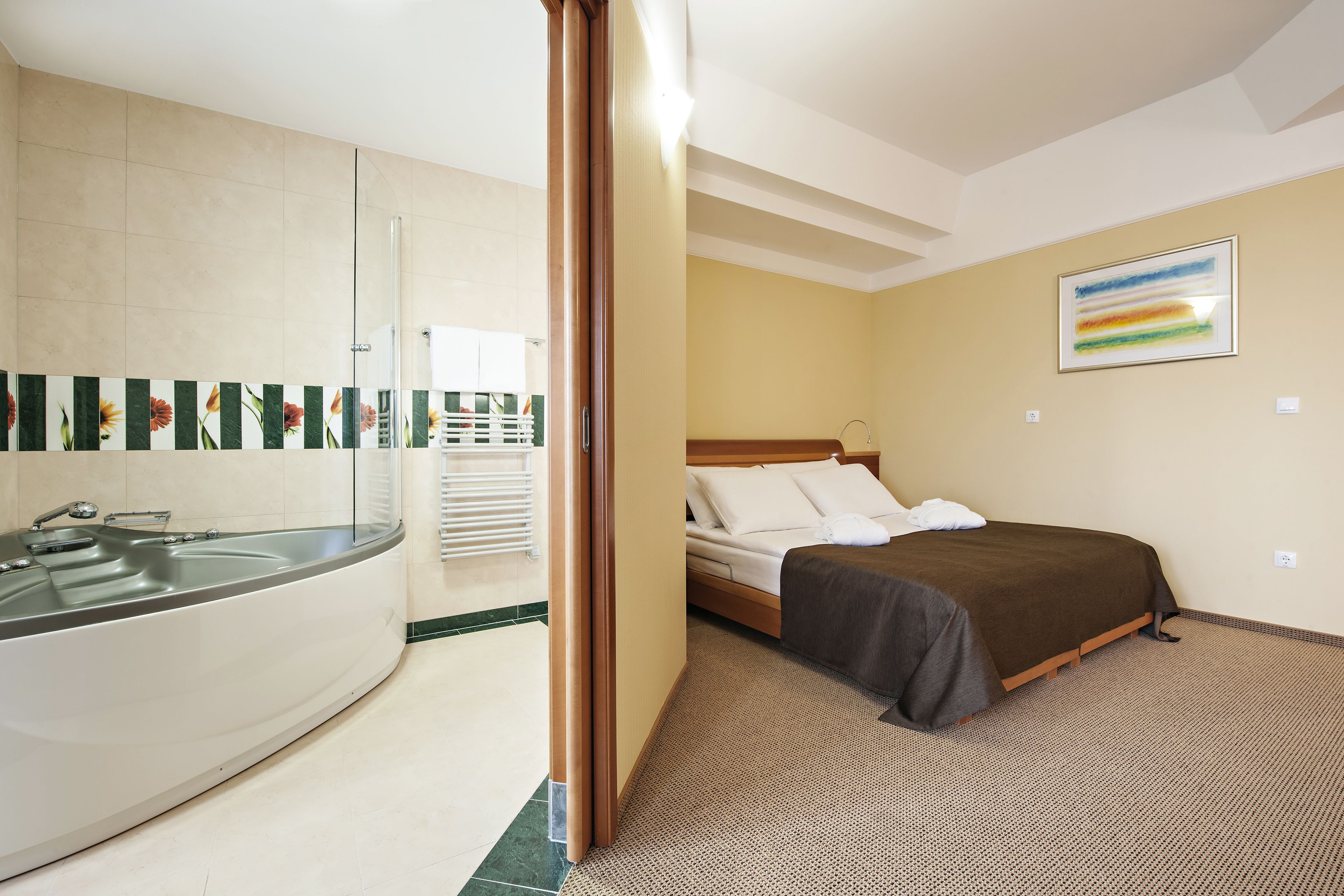 A hotel room with a bed, a bathroom with a bathtub, and a shower.