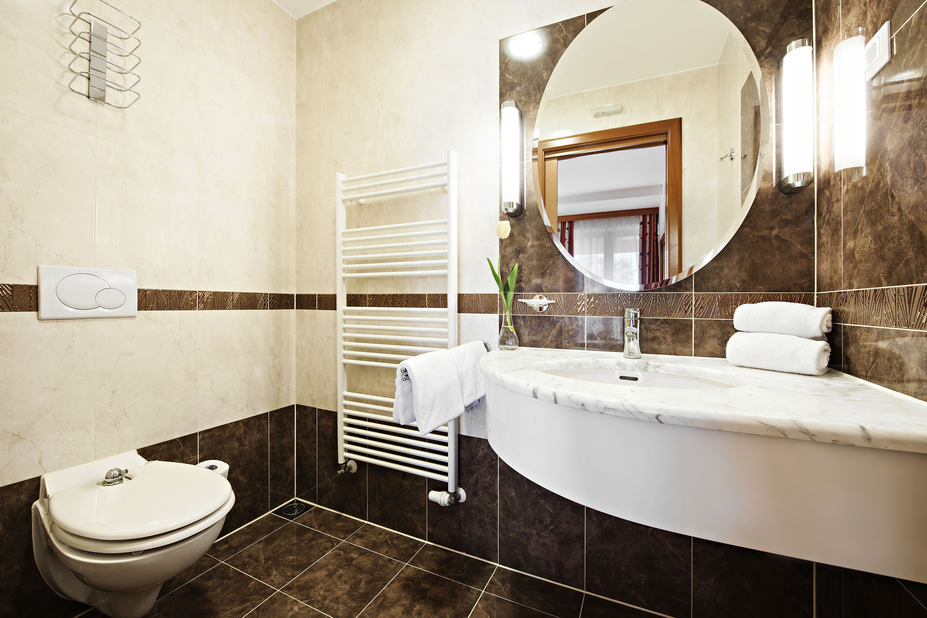 A bathroom with a toilet, a towel rack, a sink, and a mirror.