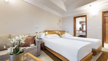 Habitación de hotel con cama, sofá, una mesita y una planta en maceta.