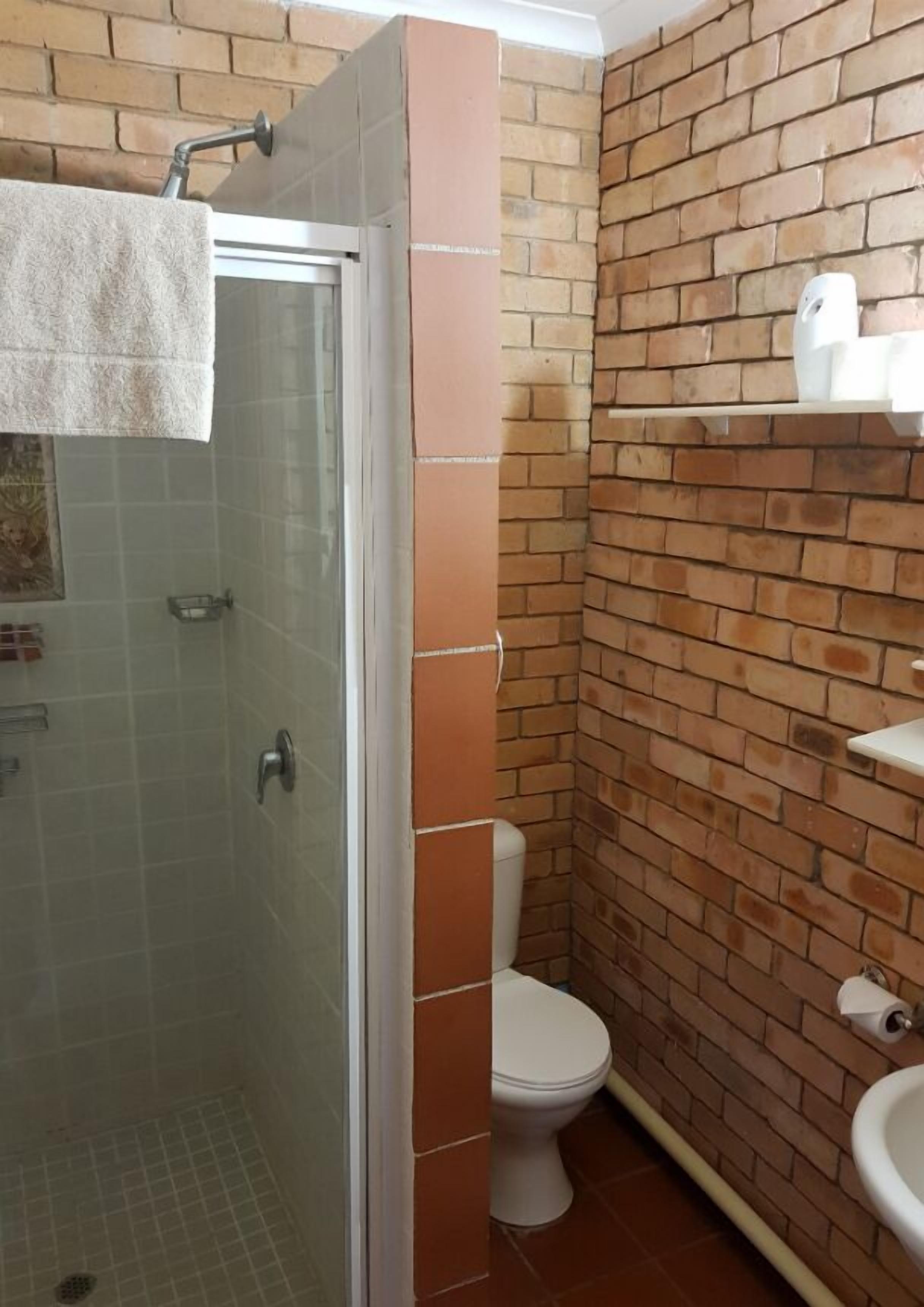 A bathroom with a glass shower enclosure, a white toilet, and a sink with a white countertop.