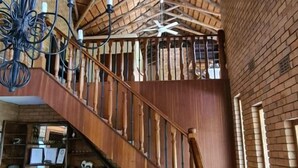 A spacious interior with a wooden staircase, a chandelier, and a ceiling fan. - Dreamfields Guesthouse (Mbombela)