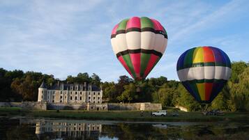 Dos globos aerostáticos sobre un cuerpo de agua, con un edificio histórico al fondo.