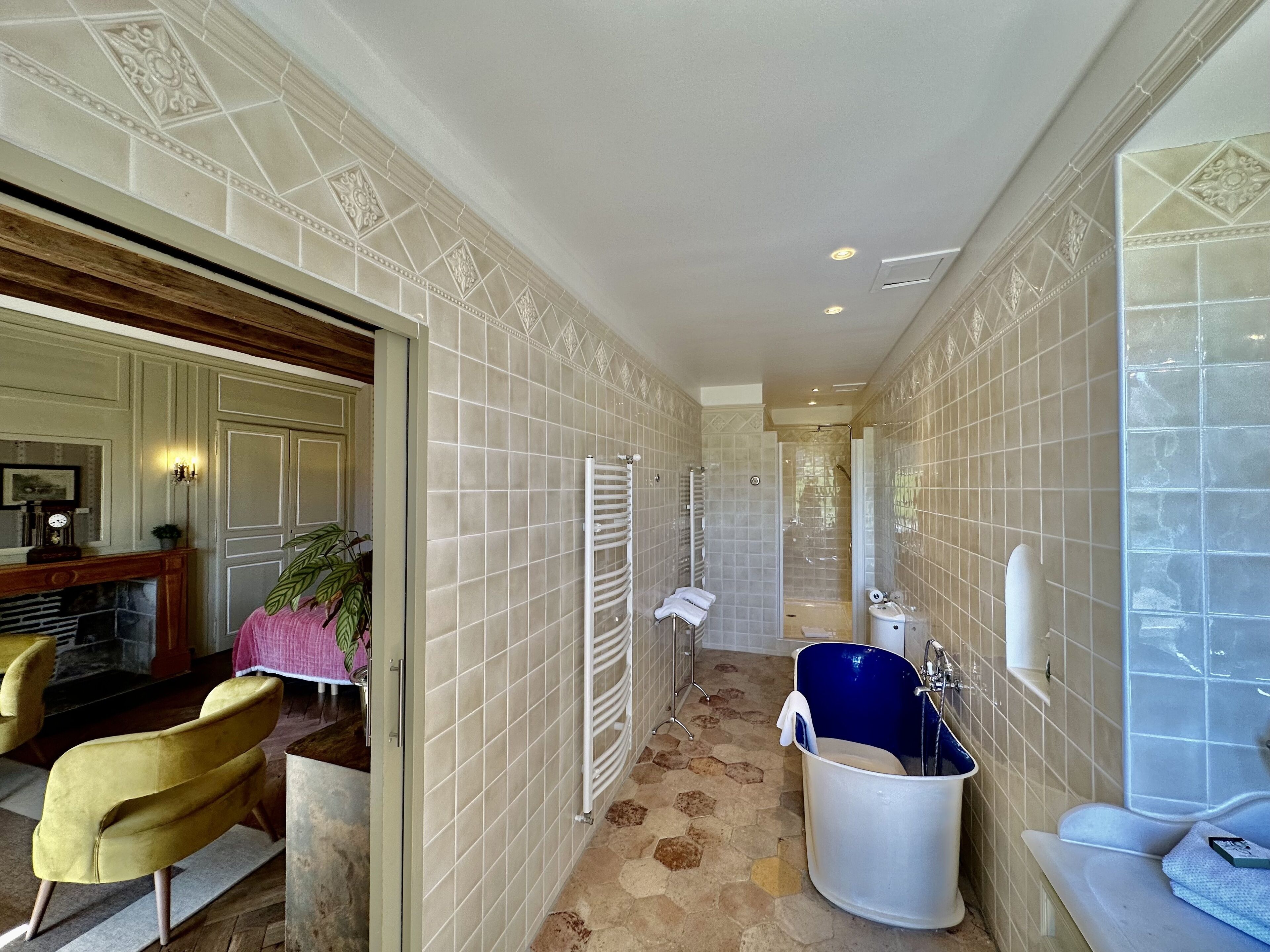 A narrow hallway with a bathtub, a radiator, and a door leading to another room.