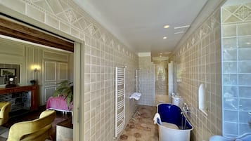 A narrow hallway with a bathtub, a radiator, and a door leading to another room.