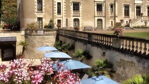 A large, historic building with a turret, multiple chimneys, and a well-maintained garden with outdoor seating. - Château des Arpentis (Saint-Regle)