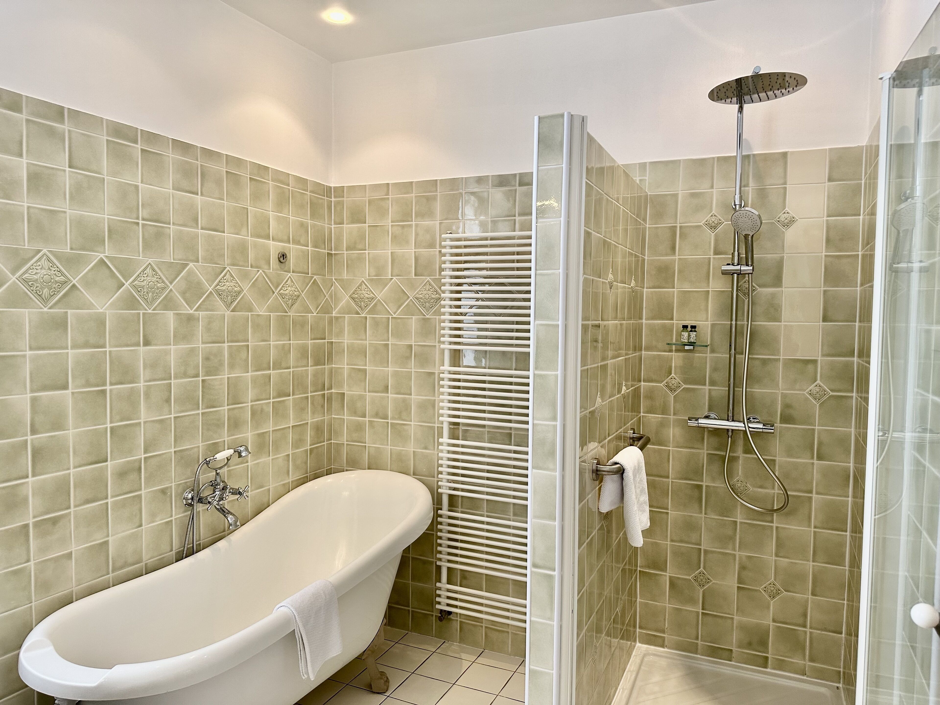 A bathroom with a freestanding bathtub, a glass-enclosed shower, and a towel rack.