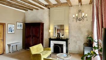 Una habitación con chimenea, un sillón amarillo, una mesa redonda y un aparador de madera.