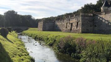 Eine historische Steinmauer mit einem schmalen Bachlauf entlang.