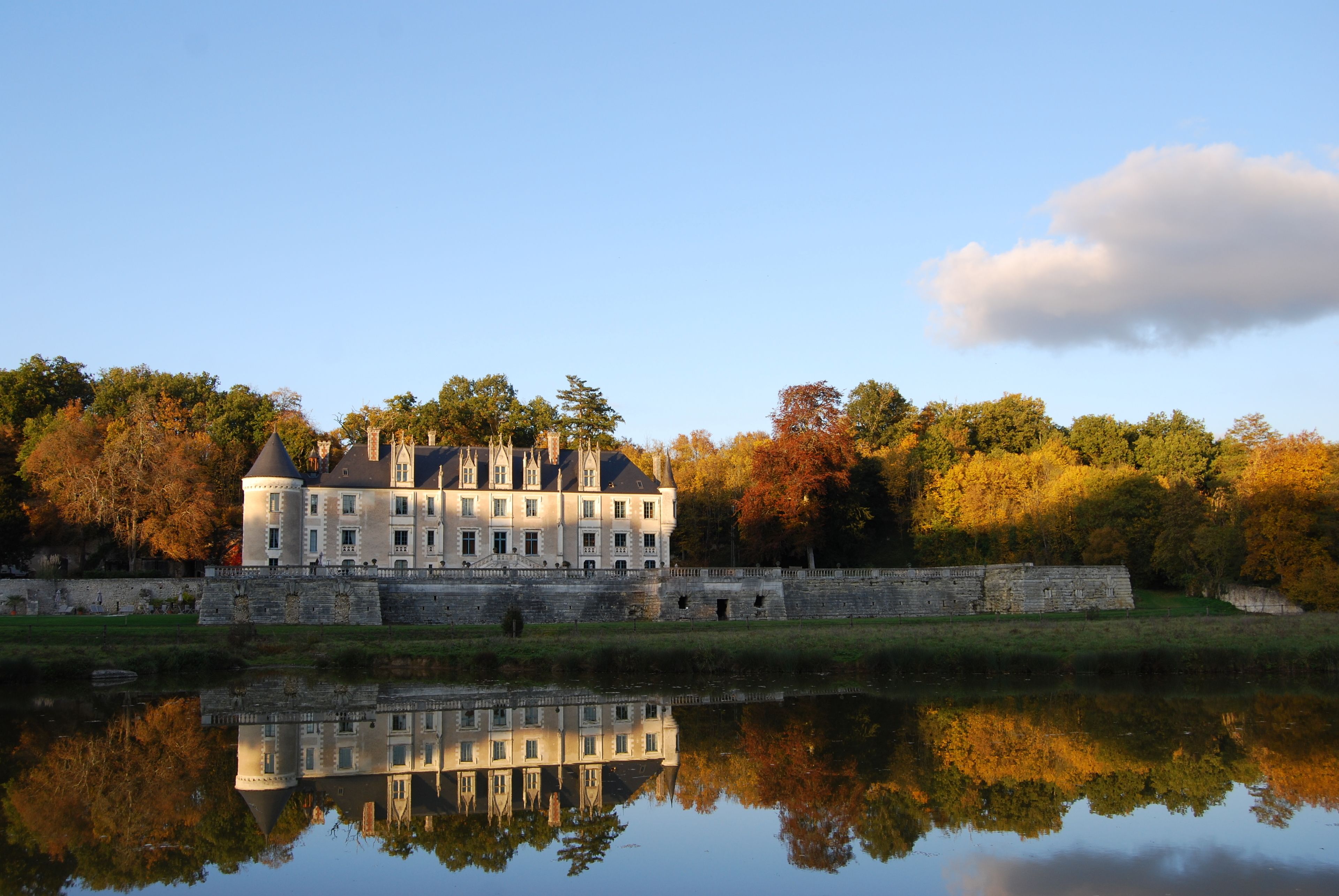 A large, historic building with a moat and reflection in the water.