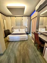 Una habitación de hotel con una cama grande, un escritorio, una silla, una lámpara de escritorio, un teléfono y un espejo.