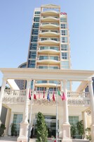 Un hotel con una entrada destacada, varios balcones y banderas.