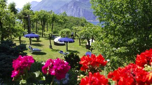 A garden with outdoor seating and a view of mountains. - Hotel Querceto by Double Hospitality (Malcesine)