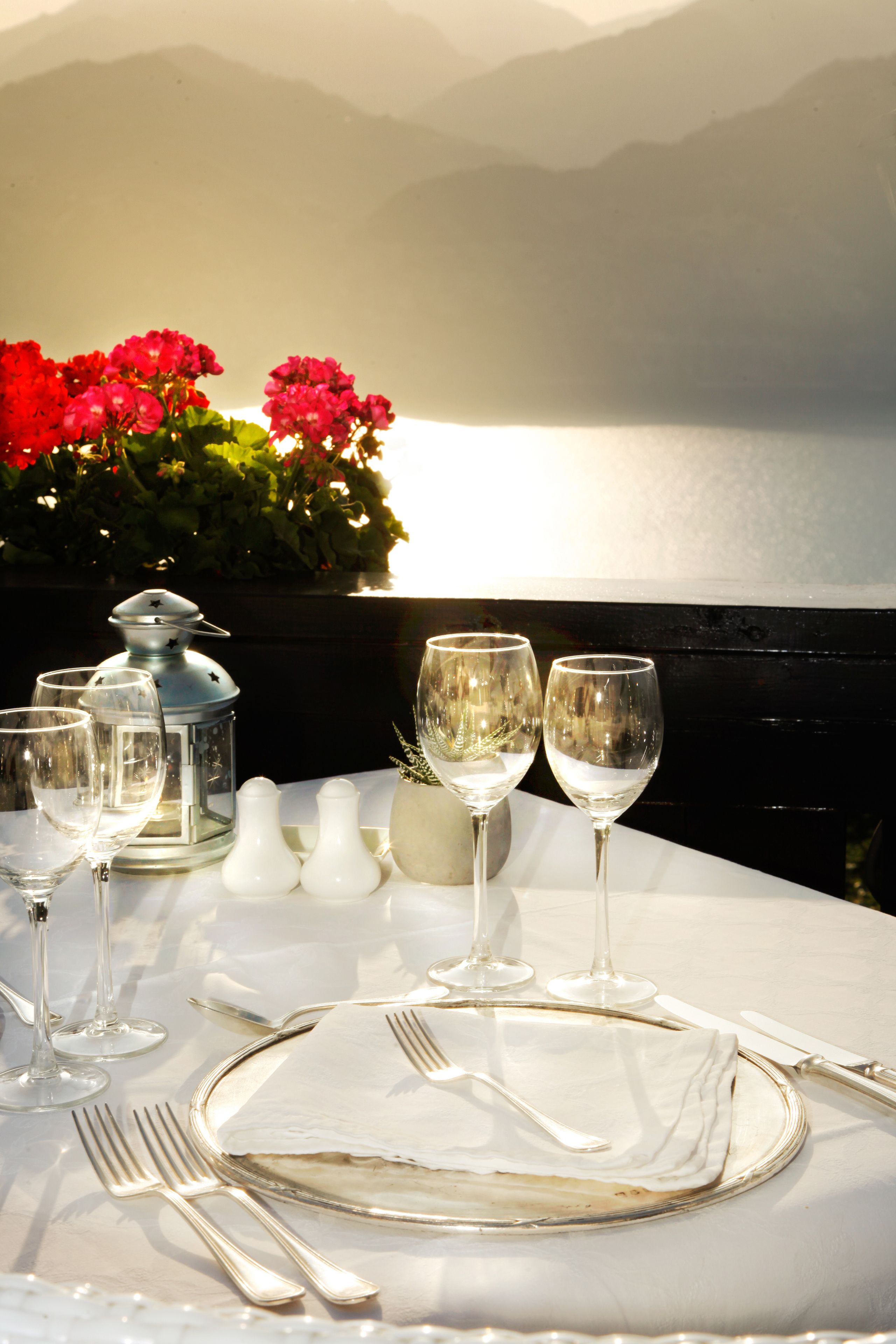 A table set for a meal with a view of the sea and mountains in the background.