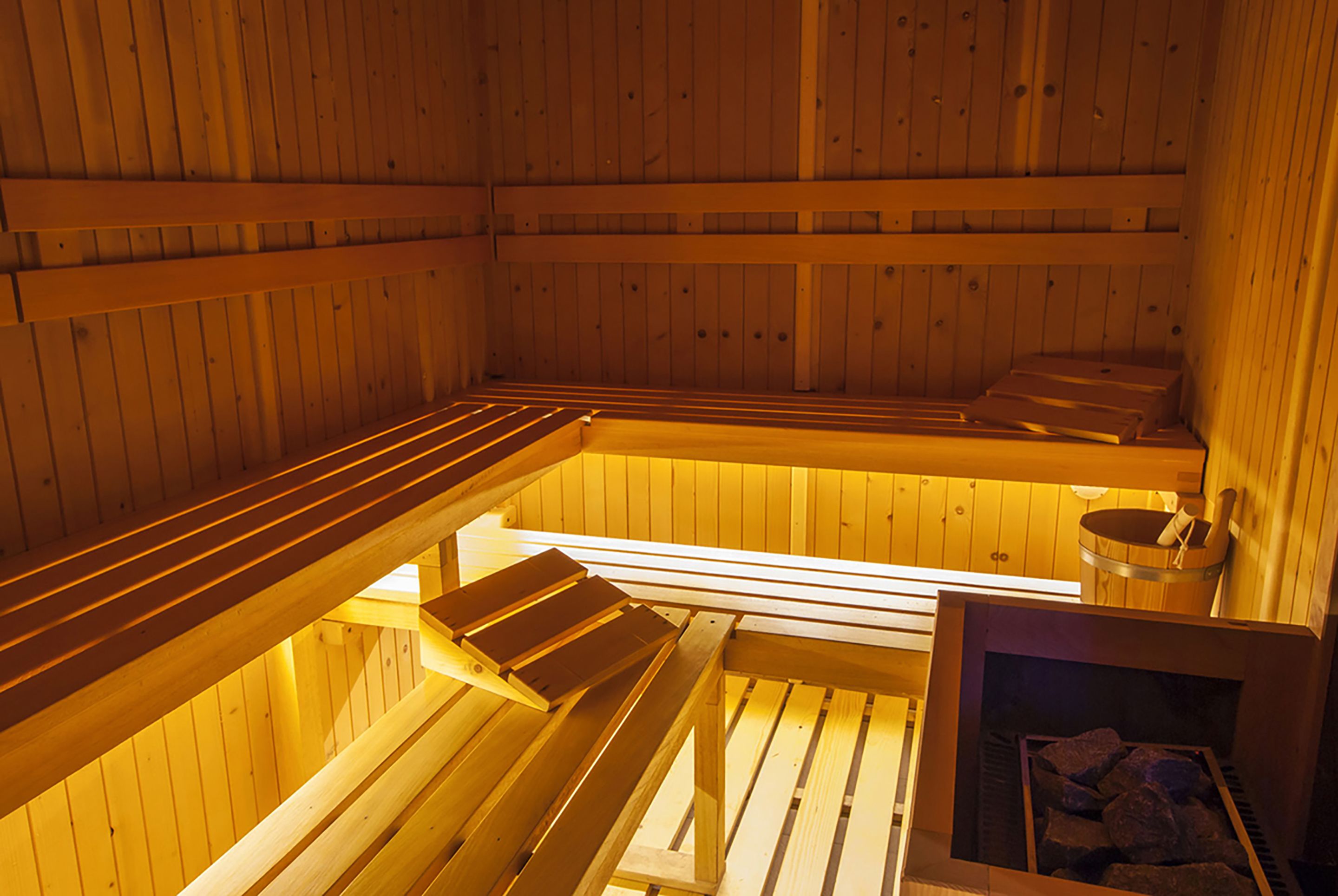 A sauna with wooden benches and a stone heating element.