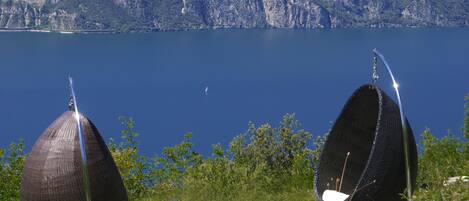 Two large, spherical, metallic structures with metal poles, set against a backdrop of a mountainous landscape and a calm lake.