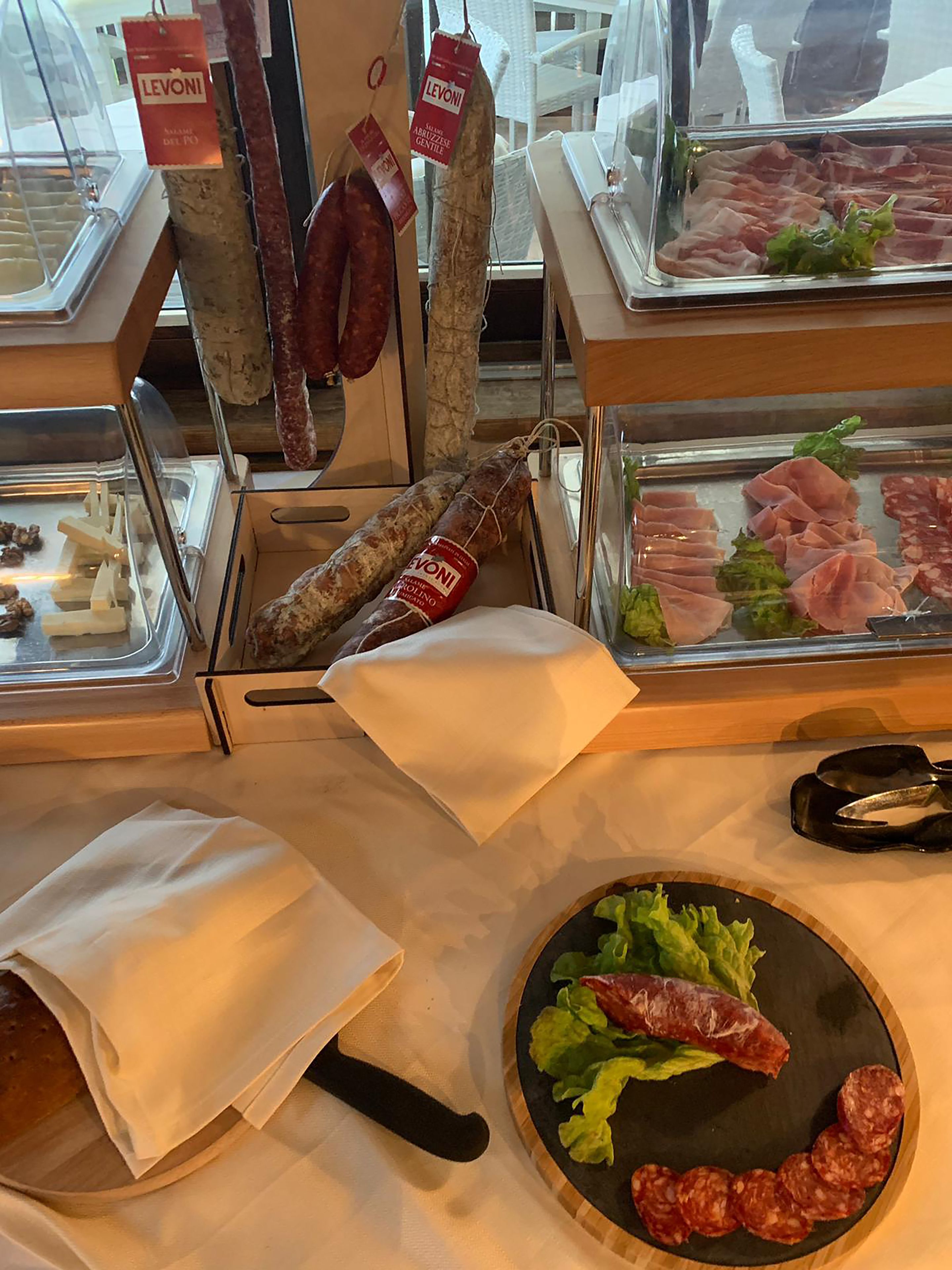 A deli counter with various cured meats and cheeses displayed in glass cases.