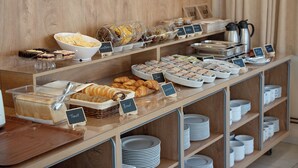 Un buffet proposant une variété d’aliments, chacun étant clairement identifié, notamment des toasts, du pain, des croissants et diverses pâtisseries.