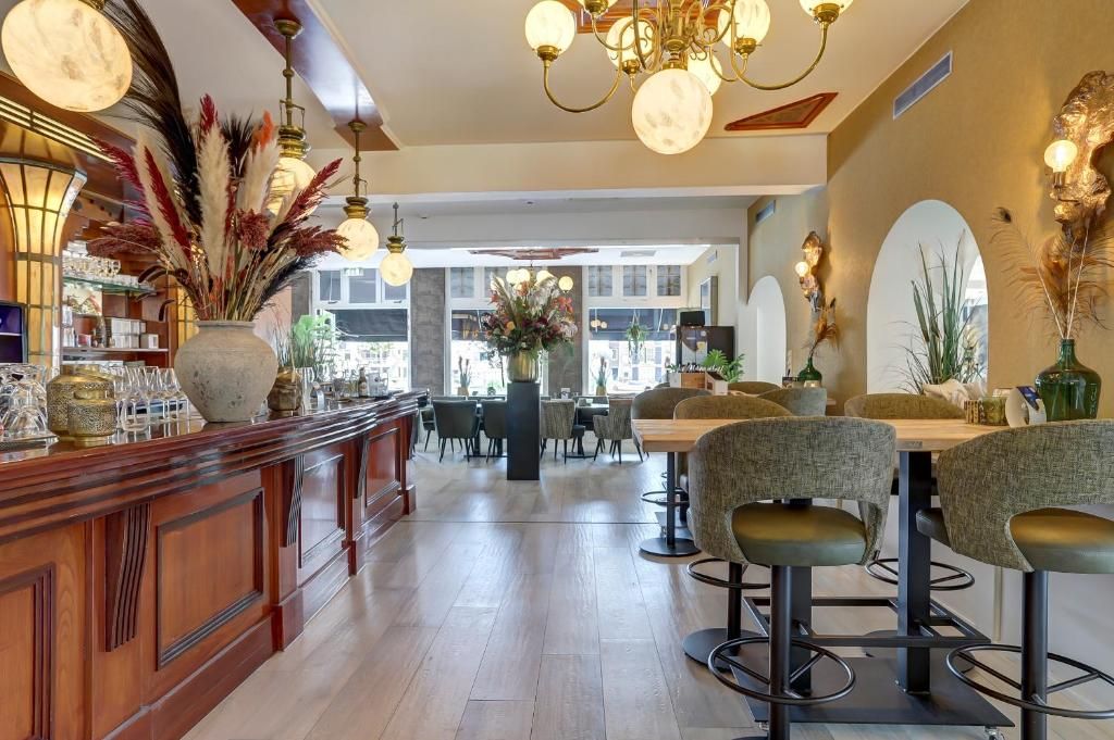 A bar area with a wooden counter, bar stools, and decorative plants.