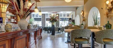 A bar area with a wooden counter, bar stools, and decorative plants.