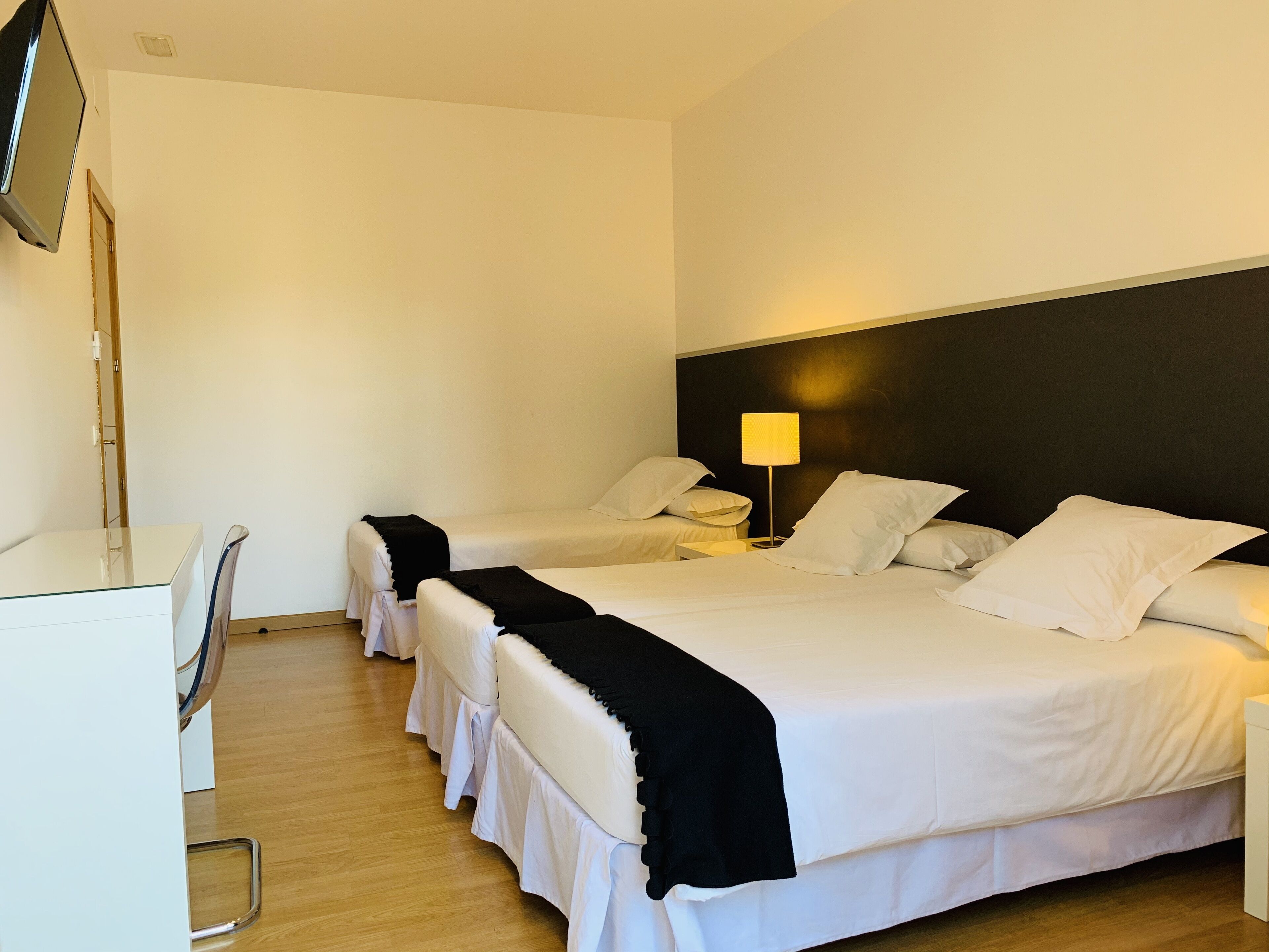 Habitación de hotel con dos camas, un escritorio y una televisión.