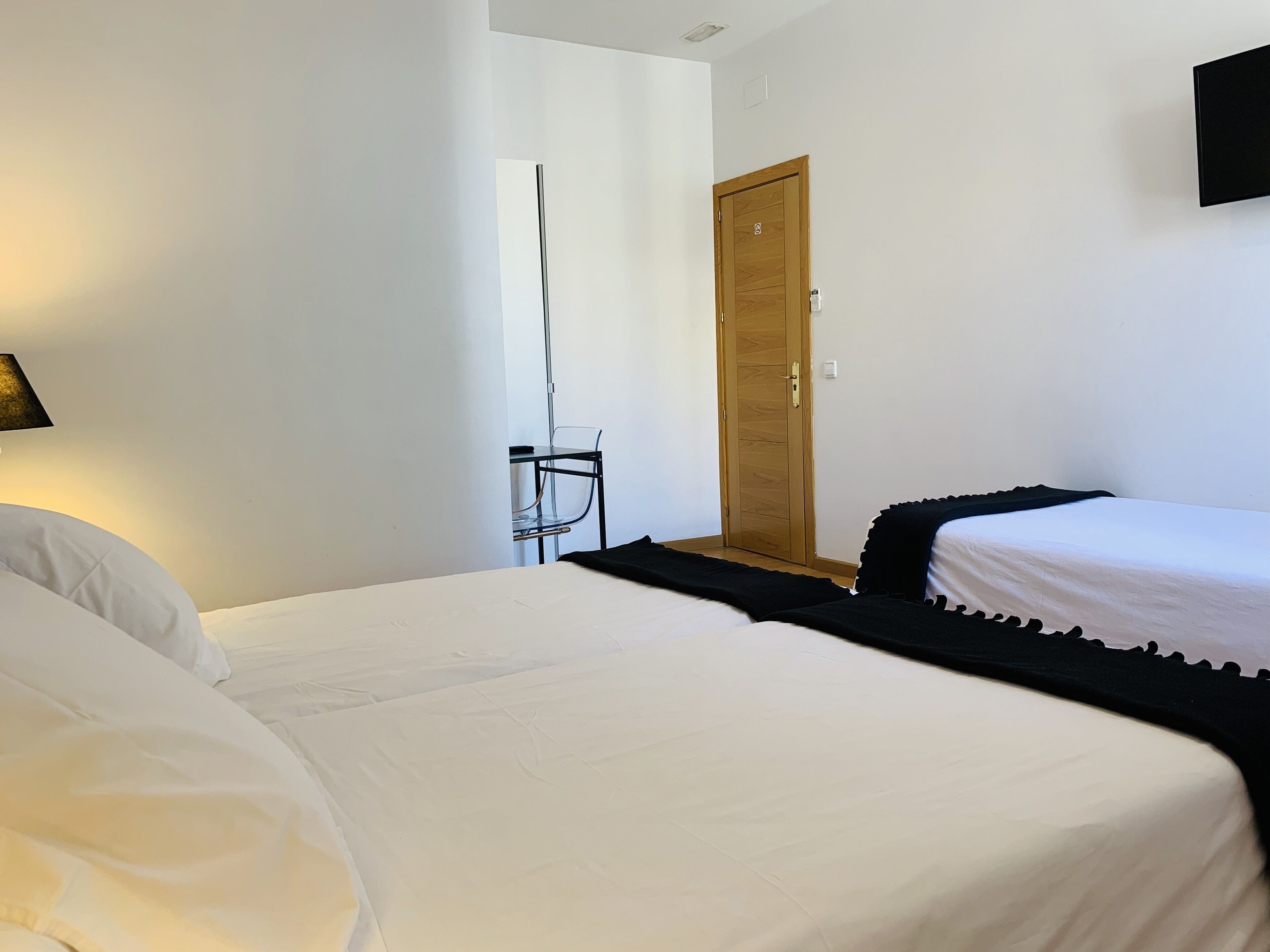 A bedroom with two beds, a wooden door, and a chair.