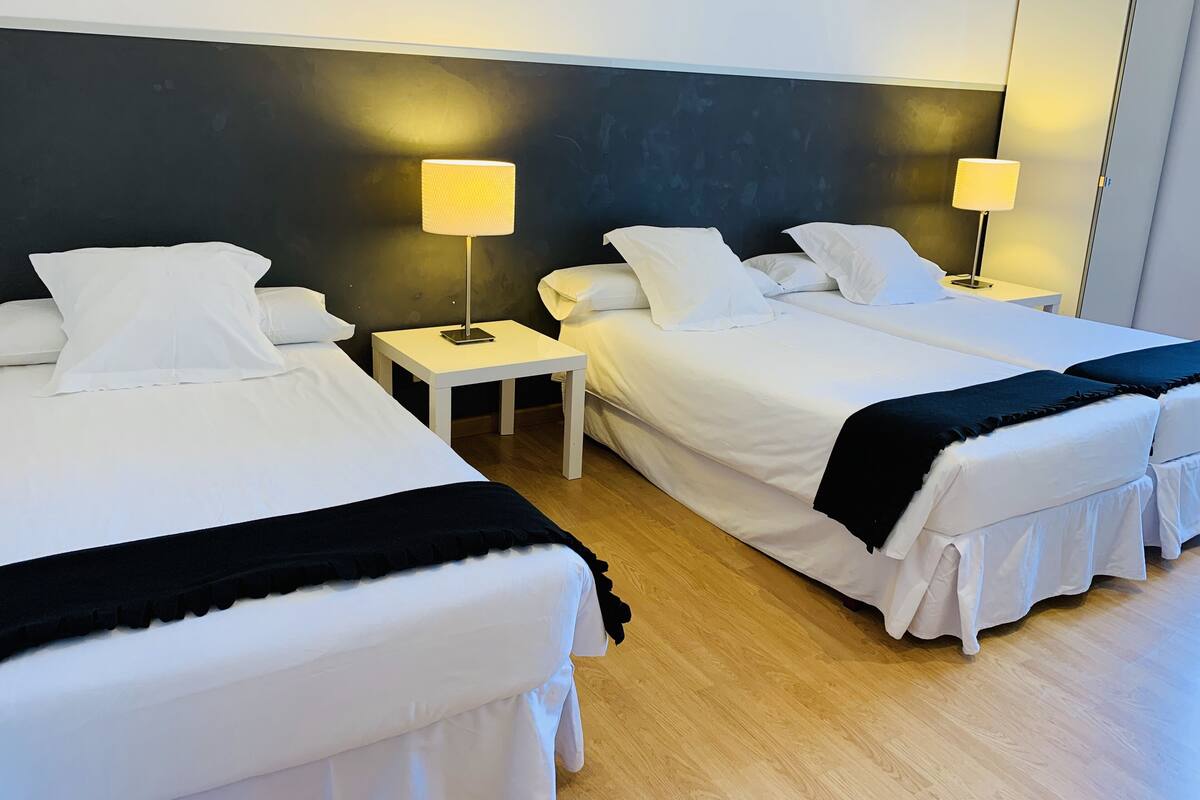 A hotel room with two beds, white bedding, and bedside lamps.