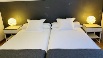 Een tweepersoonsbed met witte lakens en twee bedlampjes.