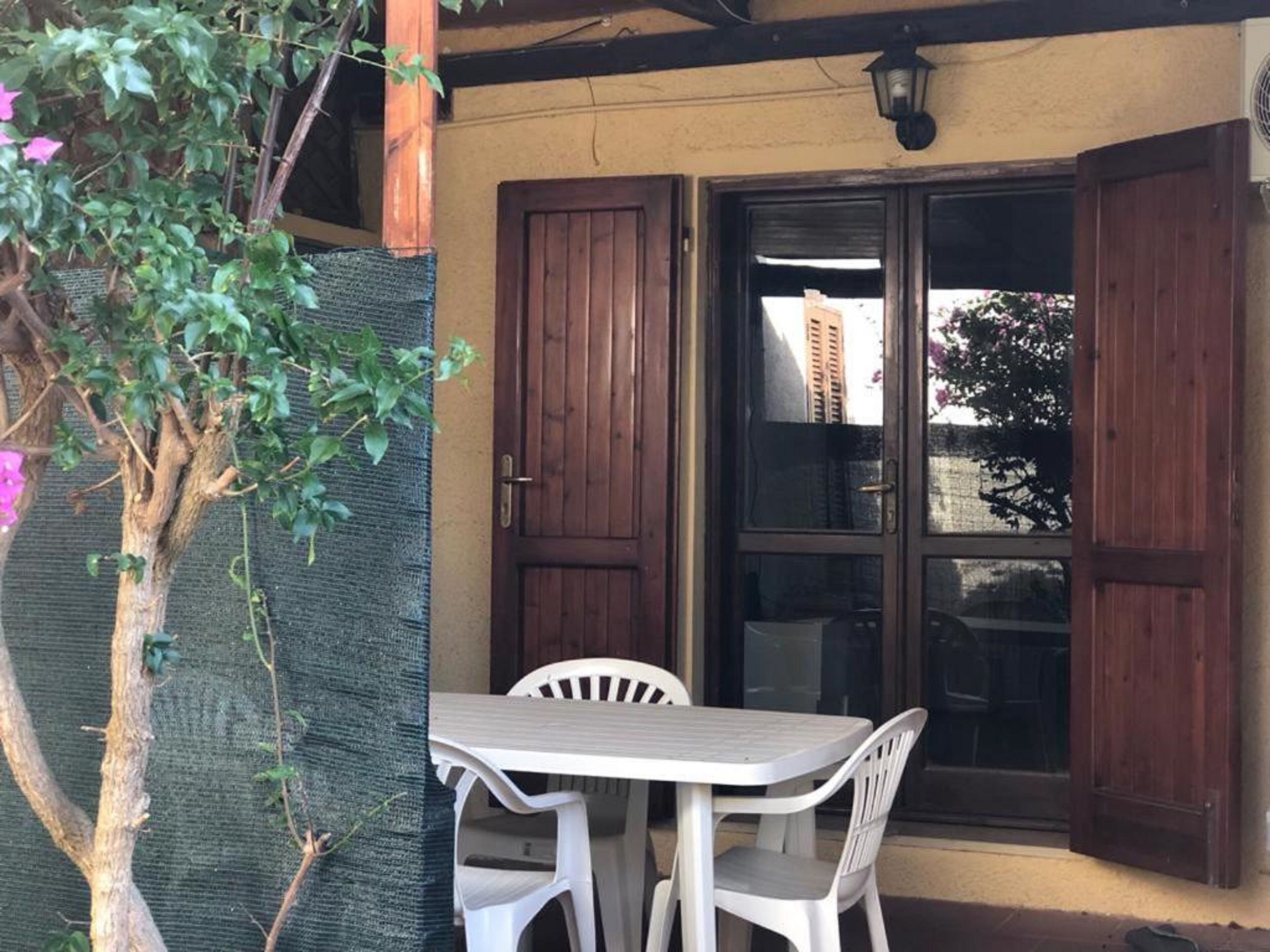 A patio with a table and chairs, a wooden door, and a view of buildings in the background.