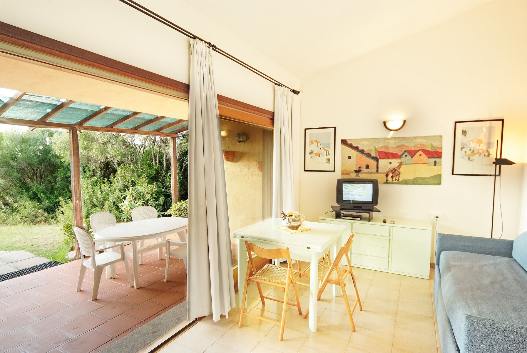 Una habitación con una mesa de comedor, sillas, televisor y obras de arte en la pared.