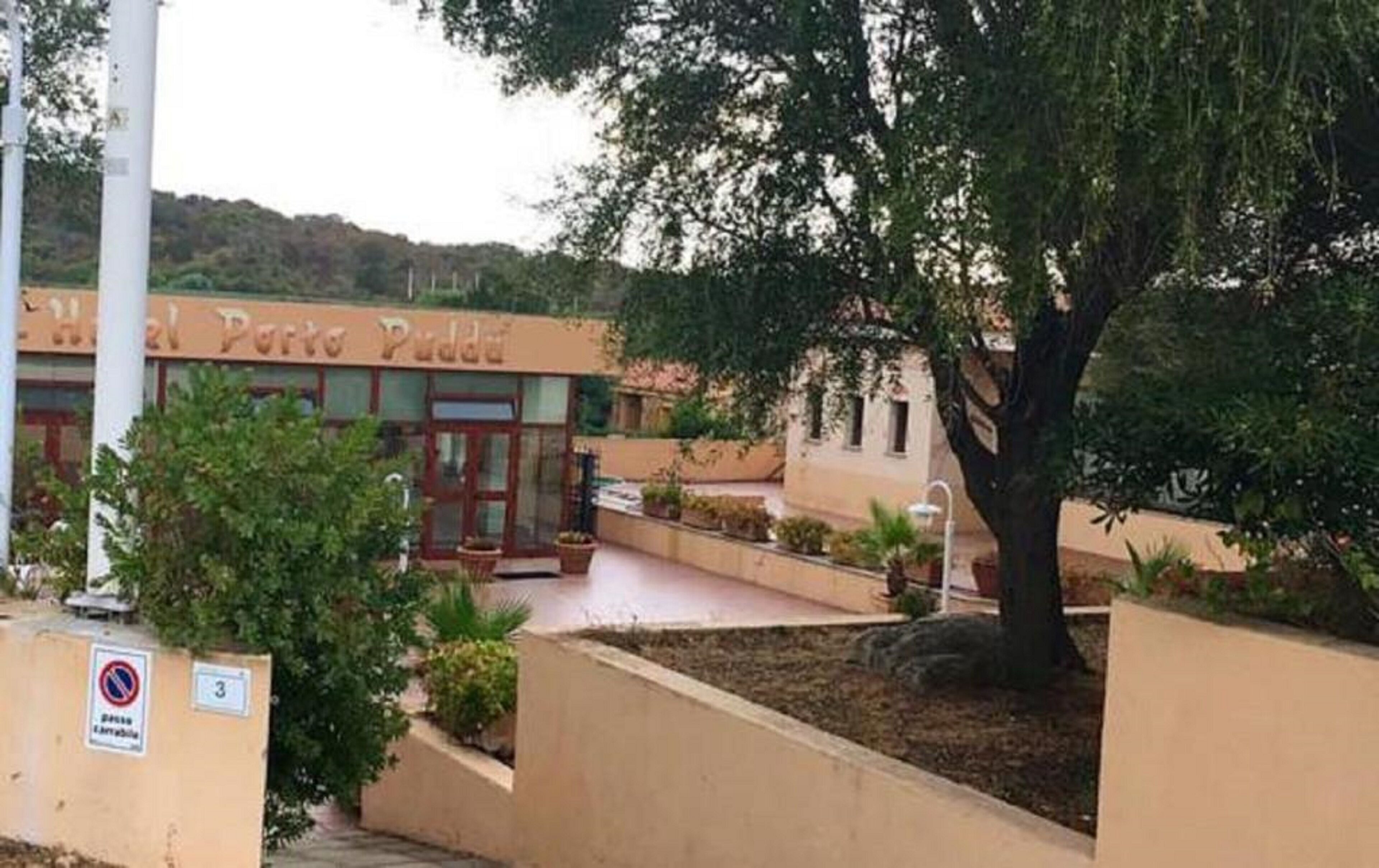 A hotel named "Hotel Porto Puttos" with a courtyard, outdoor seating, and a large tree.