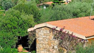 Un edificio de piedra con techo de tejas, rodeado de abundante vegetación y un jardín bien cuidado.