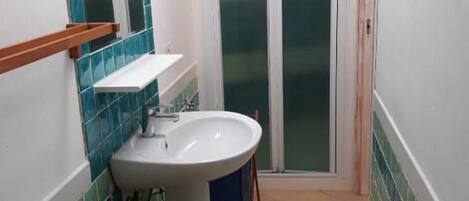 Un bagno stretto con un lavandino bianco, uno specchio con piastrelle blu e una sedia in legno.